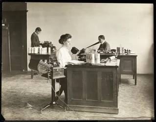 Widok wnętrza kobiety piszącej na maszynie do dyktowania i mężczyzny dyktującego do innej maszyny w Edison Phonograph Co., West Orange, New Jersey, 1903 (odbitka żelatynowa)